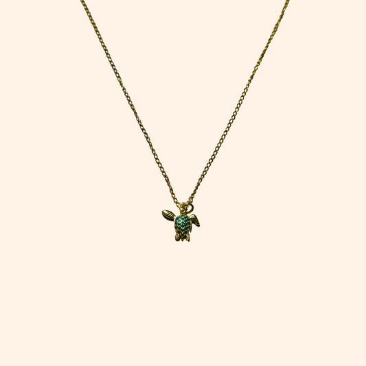 The Green Turtle Necklace by Roots Jewellery is a gold-plated chain adorned with an aquatic charm, showcasing a turtle-shaped pendant embellished with small turquoise stones.