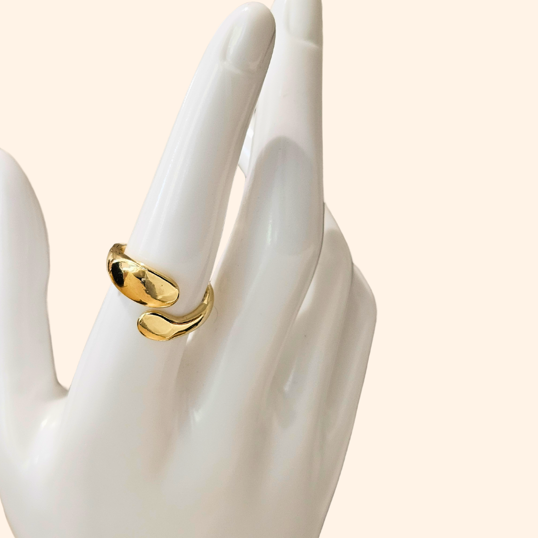 Discover the Double Twist Gold Ring by Roots Jewellery, showcasing a gold open-ended design with smooth, curved elegance on a light background. This exquisite piece ensures a perfect fit every time with its adjustable sizing feature.