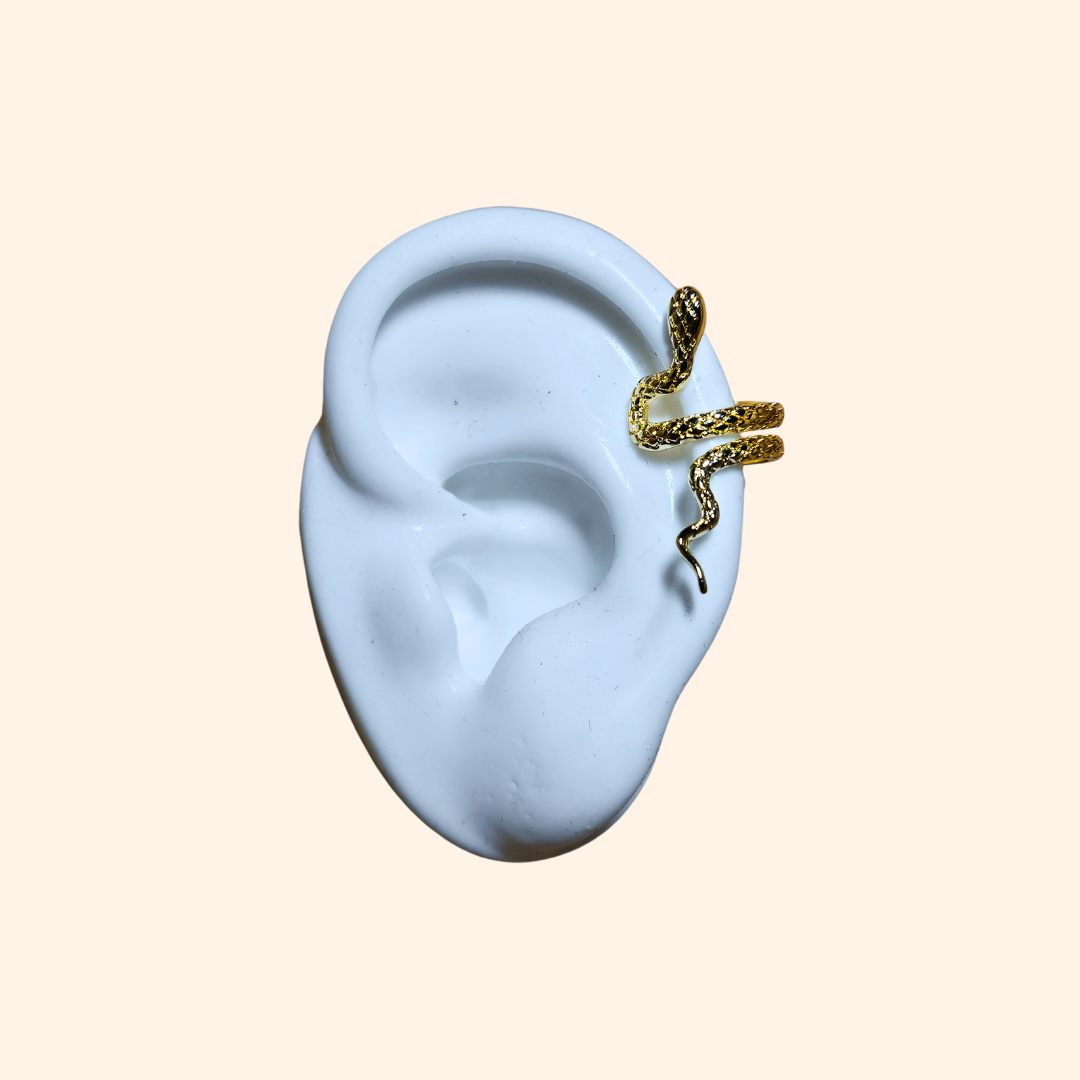 Displayed on a plain background, the captivating gold-plated design from Roots Jewellery, featuring intricate scales and an elevated head, mirrors the allure of their Serpentine Ear Cuff with its detailed snake artistry.