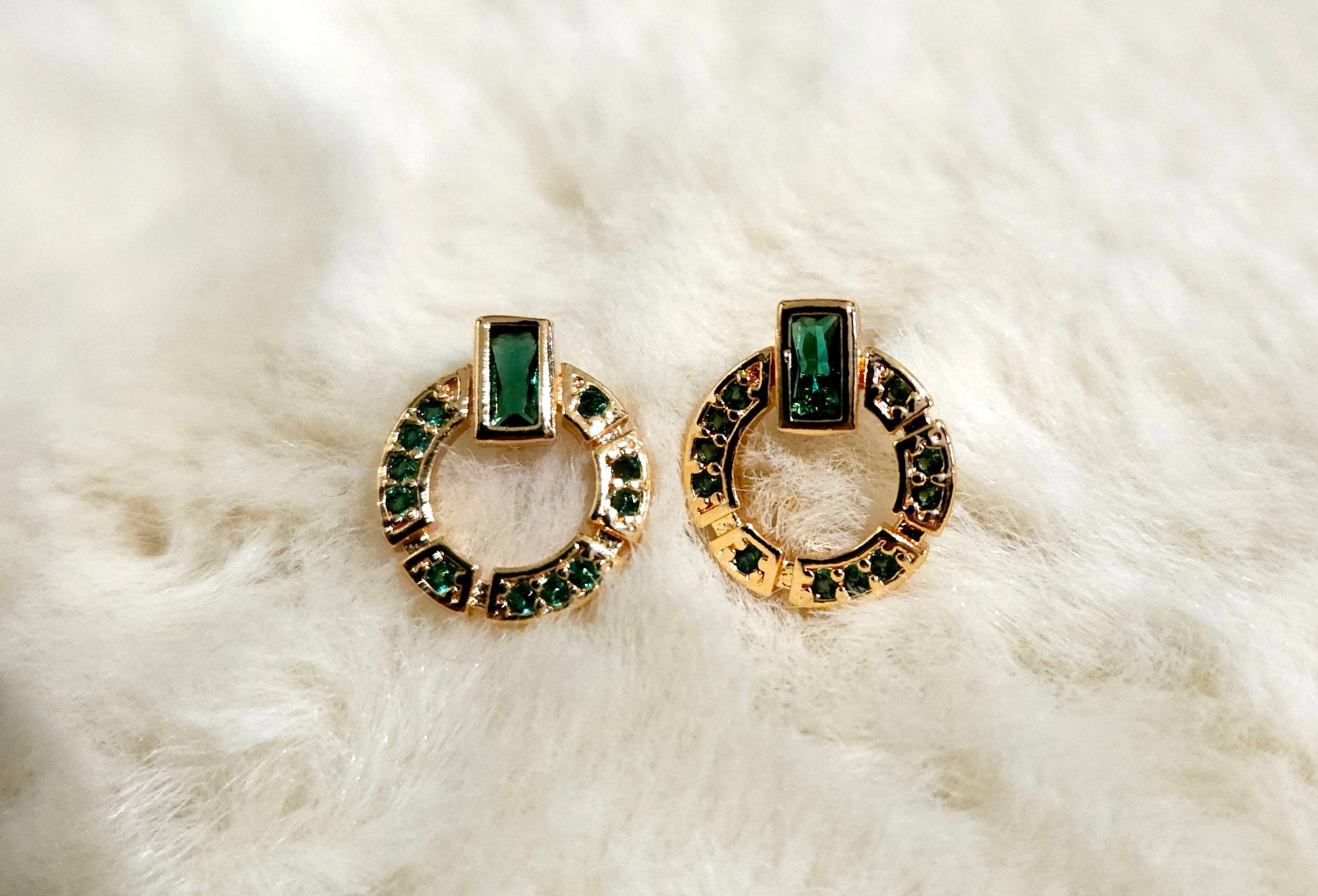 These elegant Natural Green Zircon Earrings by Roots Jewellery feature a gold-plated finish, highlighted by a distinctive circular design adorned with a striking rectangular green zircon stone at the top.