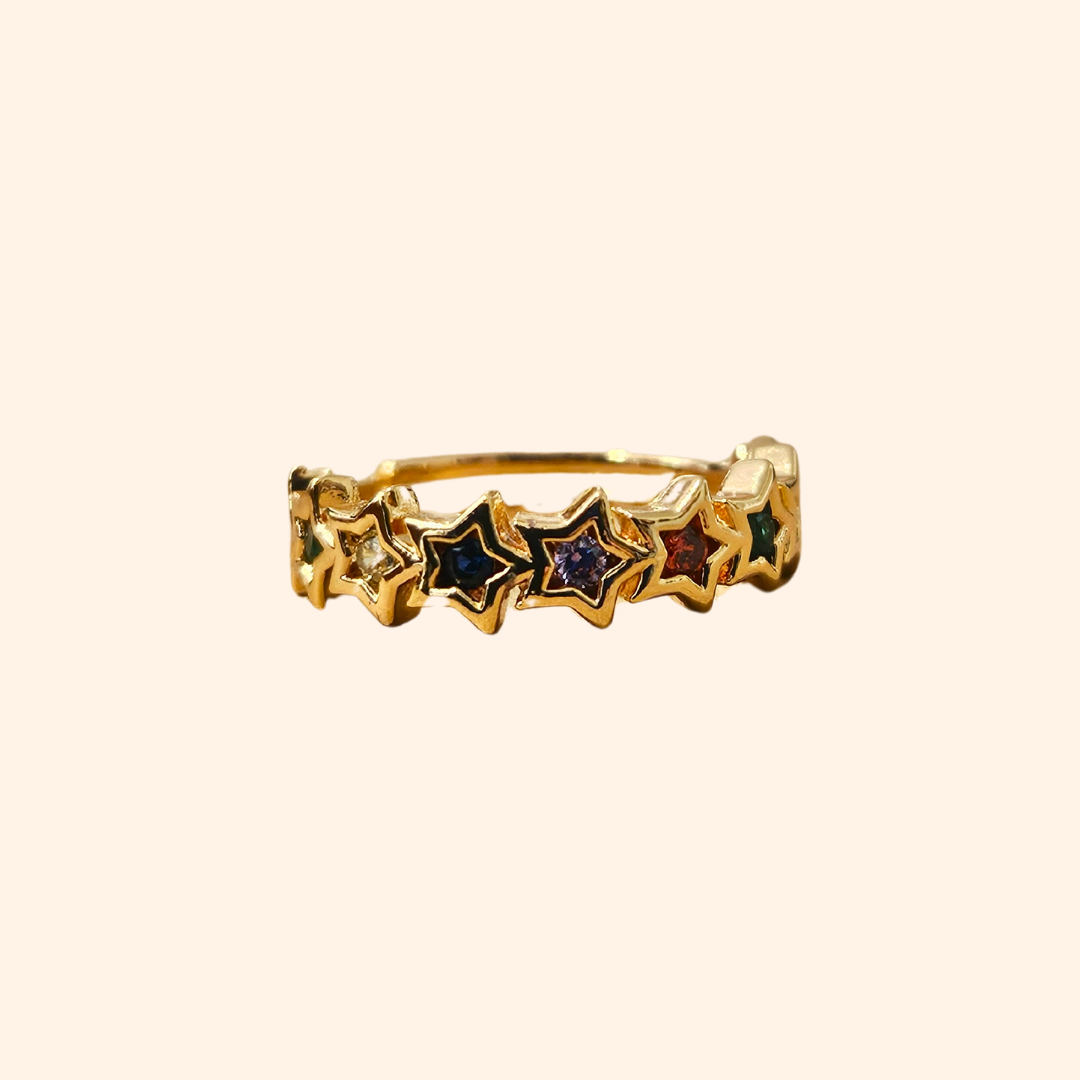 The Rainbow Stars Gold Ring from Roots Jewellery captivates with its star pattern, each embellished with shimmering gemstones. Its simple background is elevated by rhodium plating, providing a sleek finish. The adjustable design guarantees a perfect fit for any occasion.