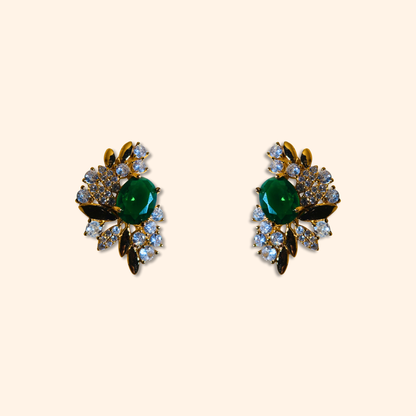 Behold the Emerald Floral Gold Earrings by Roots Jewellery, a stunning pair of vintage-inspired earrings featuring intricate floral designs with emerald green central stones surrounded by cubic zirconia.