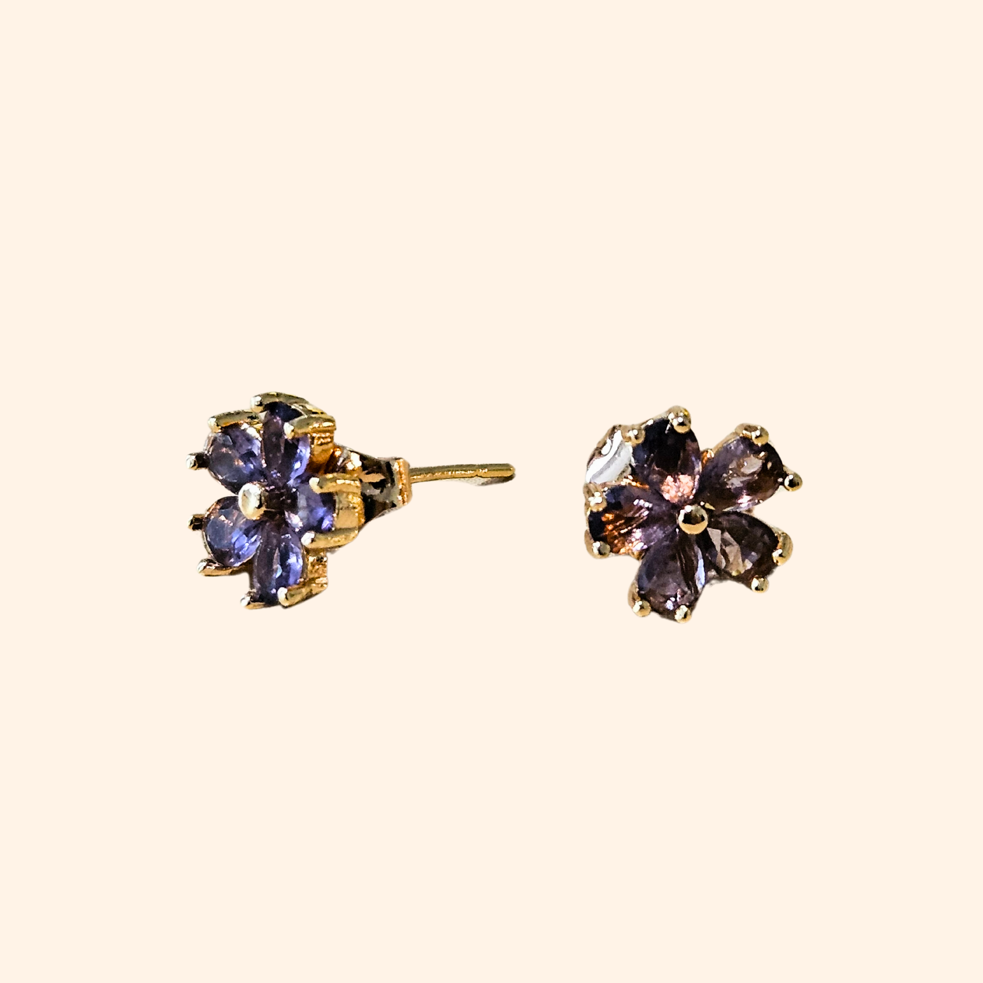 The Flowers Earrings by Roots Jewellery, featuring flower-shaped designs with purple petals and gold settings, provide a distinctive style when viewed from the front and side. These earrings are a chic complement to any ensemble.