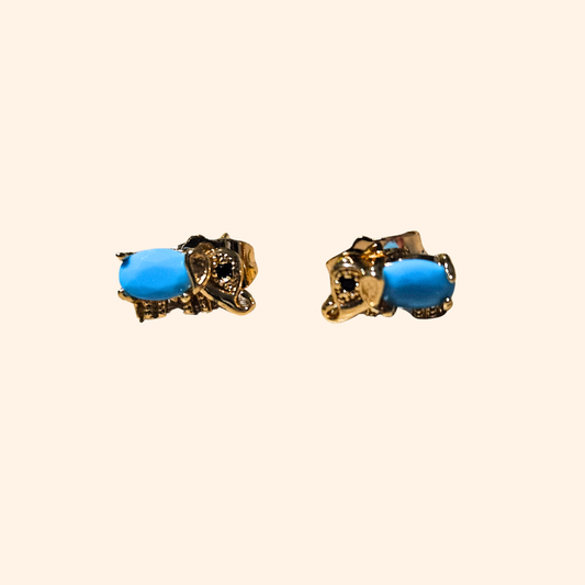 The Blue Gem Gold Elephant Earrings by Roots Jewellery shine brightly against a simple backdrop, turning into a fashionable piece that enthralls with its sophistication.