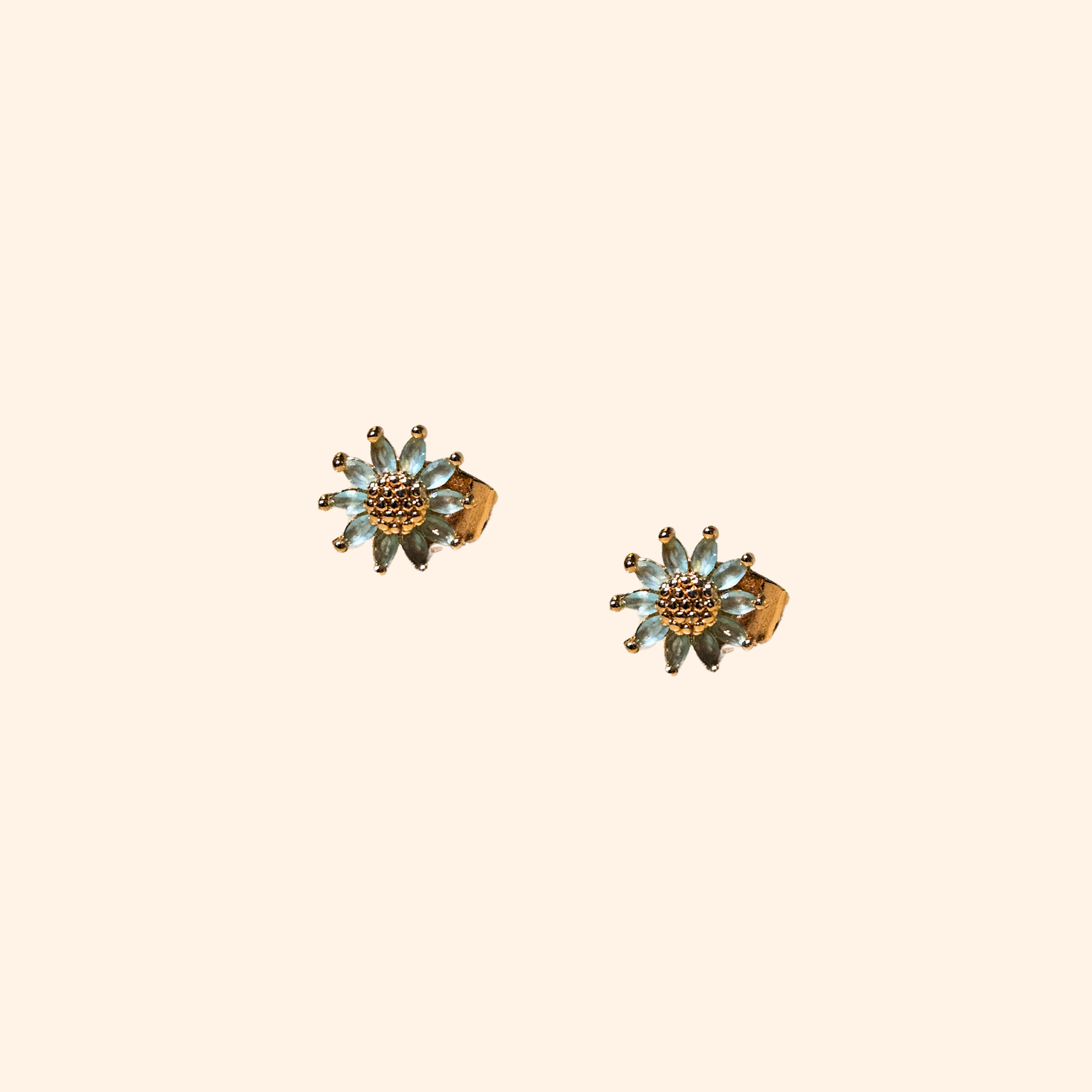 A sophisticated pair of Zirconia Margarita Earrings by Roots Jewellery, featuring pink petals and gold centers, set against a beige background and evoking the charm of Margarita blooms.