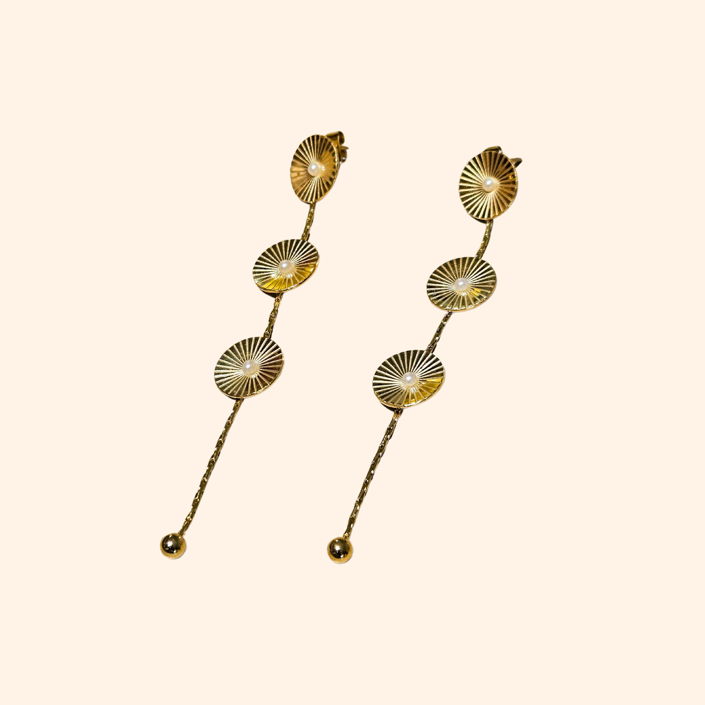 The Cosmic Earrings by Roots Jewellery feature silver and gold drop designs with circular patterns and elongated elements, providing a contemporary appeal inspired by cosmic motifs. They are showcased against a neutral backdrop.