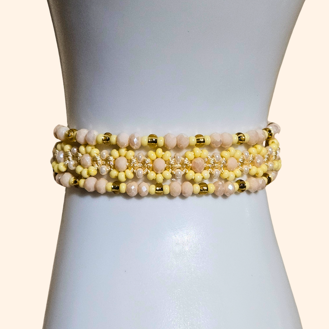 The mannequin elegantly showcases the Golden Dawn Beaded 3-Set Bracelet from Roots Jewellery, with its gold accents and pearls shimmering in harmony with subtle pastel yellows.