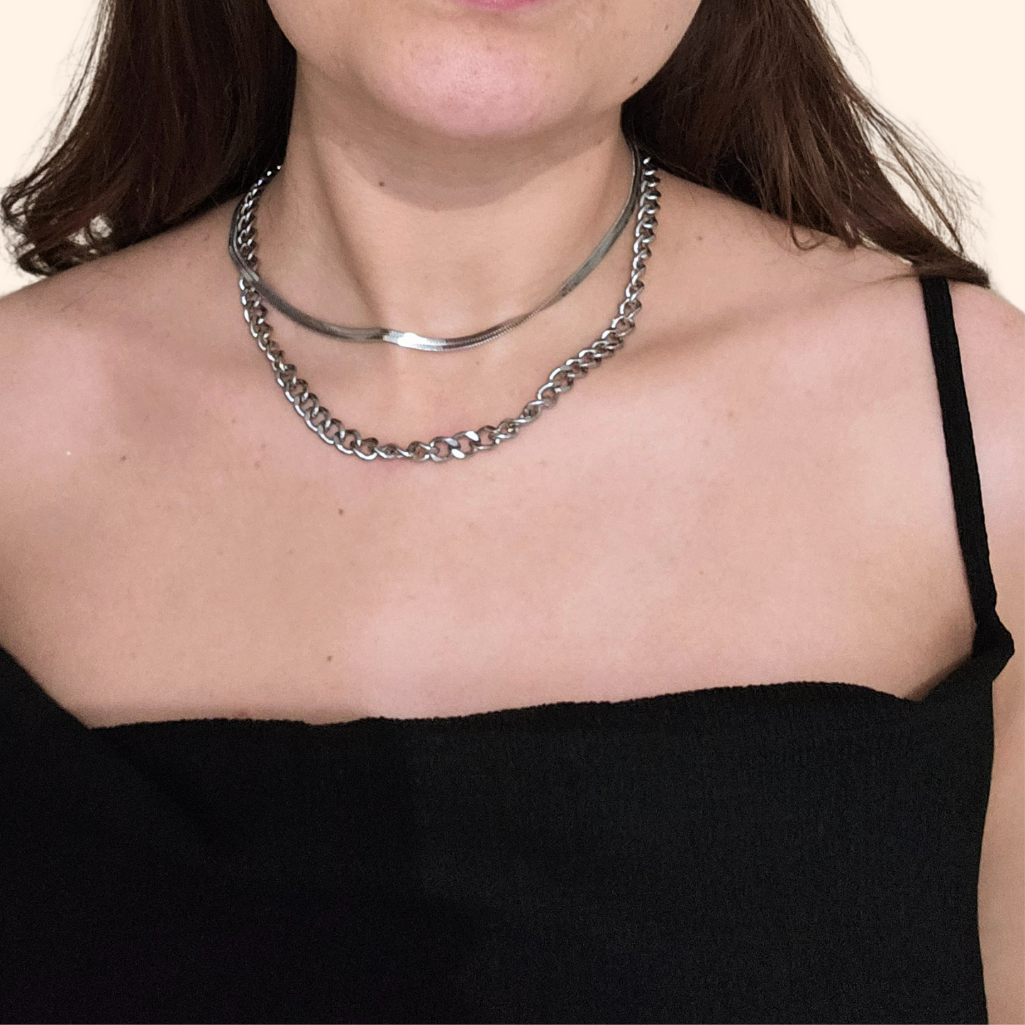 A person displays the sophisticated design of Roots Jewellery's Chain & Flat Snake Necklace with Earrings over a black sleeveless top. These versatile pieces elevate any outfit with a touch of elegance.