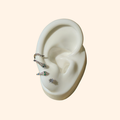 A mannequin ear displays the Sparkling Ivy Trio Earrings from Roots Jewellery, highlighting a vine-like design with a dangling earring at the top, a stud on the lobe, and a hoop adorned with zircon stones near the bottom.