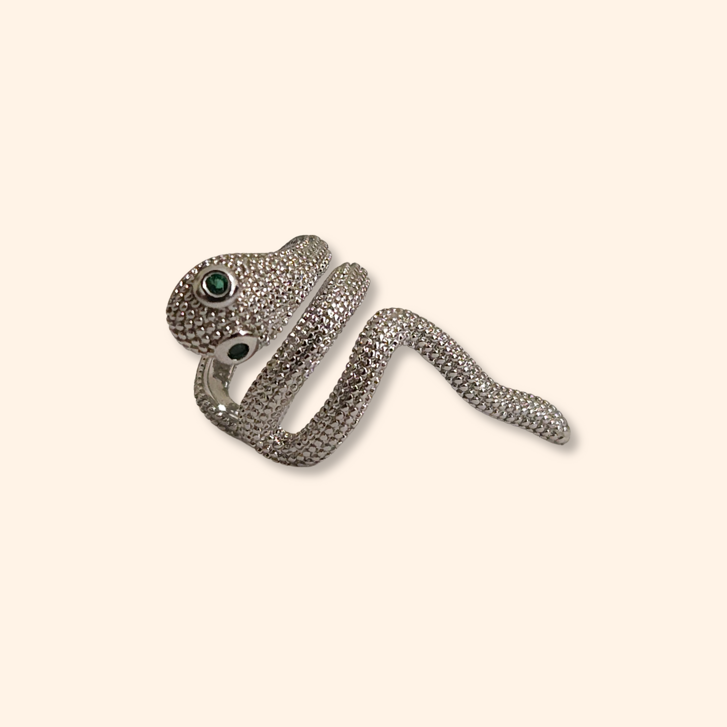 The Little Snake Ear Cuff by Roots Jewellery is a captivating fashion accessory, featuring a snake-shaped design with emerald-colored eyes that stands out beautifully against a light background.