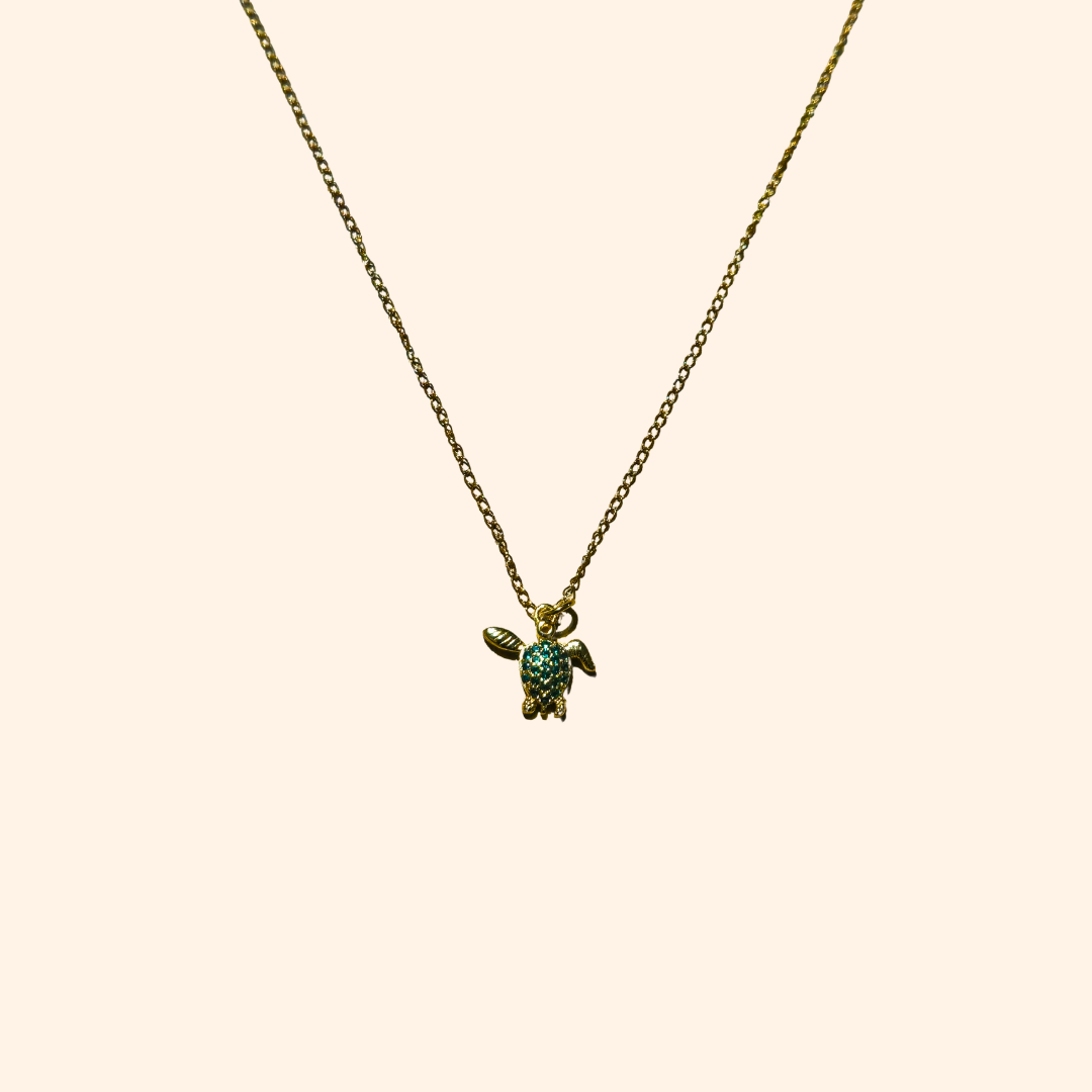 The Green Turtle Necklace by Roots Jewellery is a gold-plated chain adorned with an aquatic charm, showcasing a turtle-shaped pendant embellished with small turquoise stones.