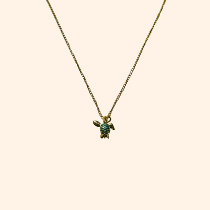 The Green Turtle Necklace by Roots Jewellery is a gold-plated chain adorned with an aquatic charm, showcasing a turtle-shaped pendant embellished with small turquoise stones.