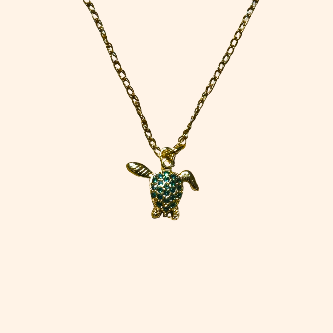 The Green Turtle Necklace by Roots Jewellery is a gold-plated chain adorned with an aquatic charm, showcasing a turtle-shaped pendant embellished with small turquoise stones.