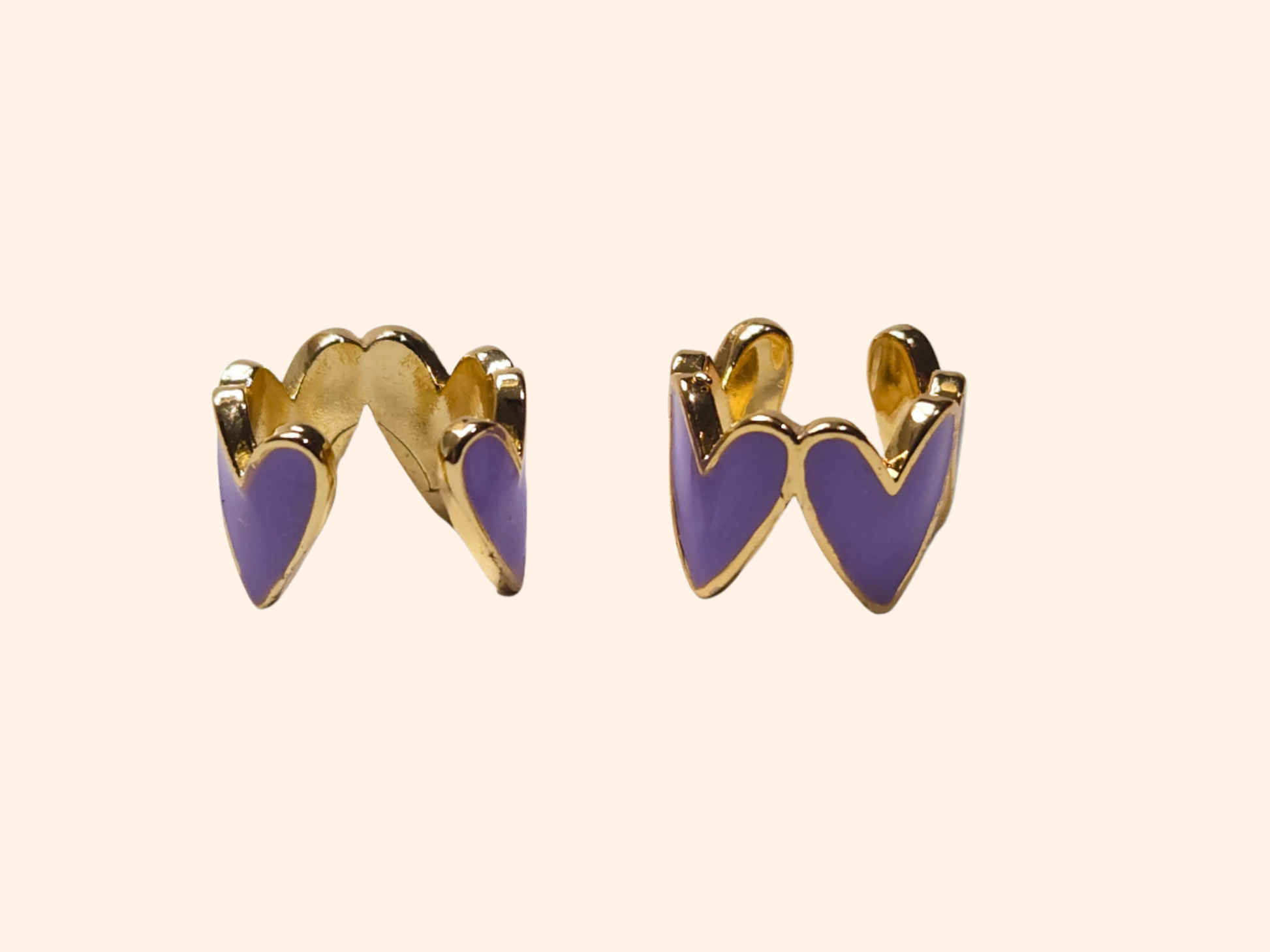 This chic accessory is the Heart-shaped Ear Cuff by Roots Jewellery, showcasing a gold finish with a repeating white heart pattern on a light beige background.
